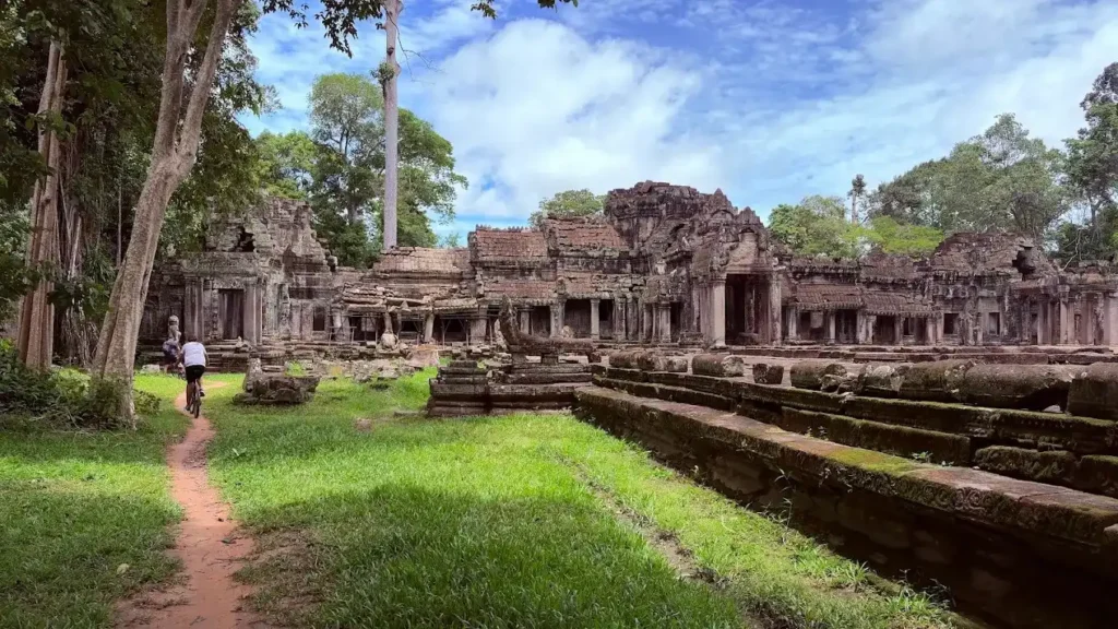 Cyclist riding a narrow trail beside an Angkor temple in Siem Reap